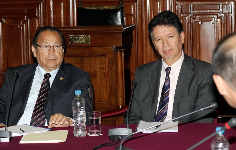 two men in suits and ties sitting at a table