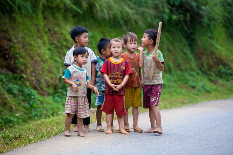 children are standing on the side of a road