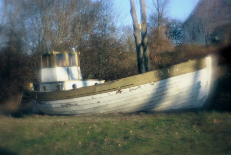 this boat has no motor and is parked in the grass