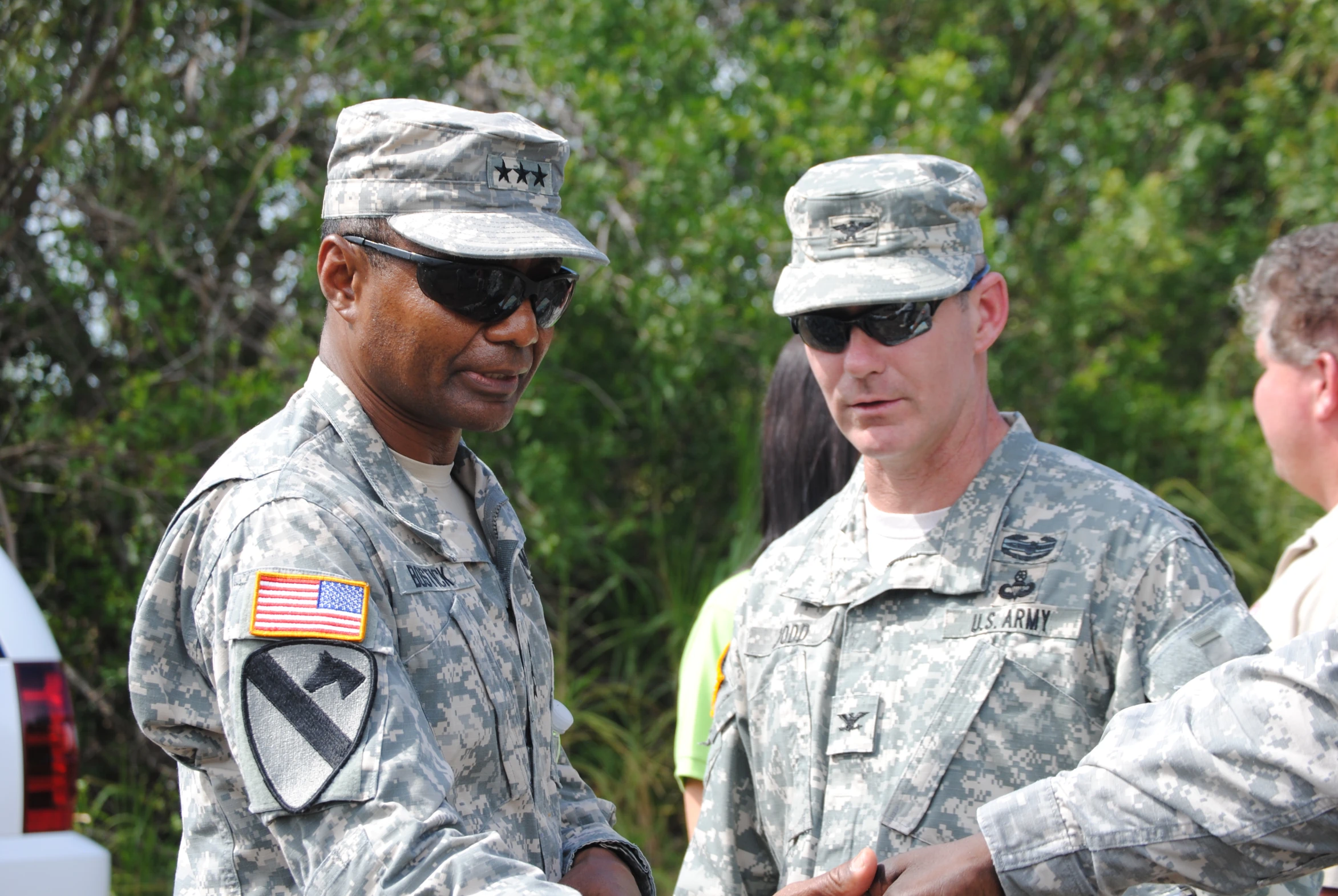 two men in uniform stand together with other people