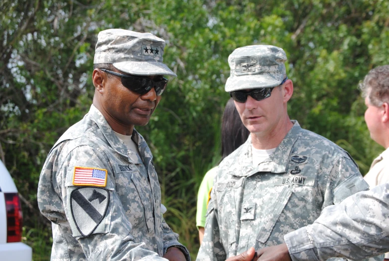 two men in uniform stand together with other people