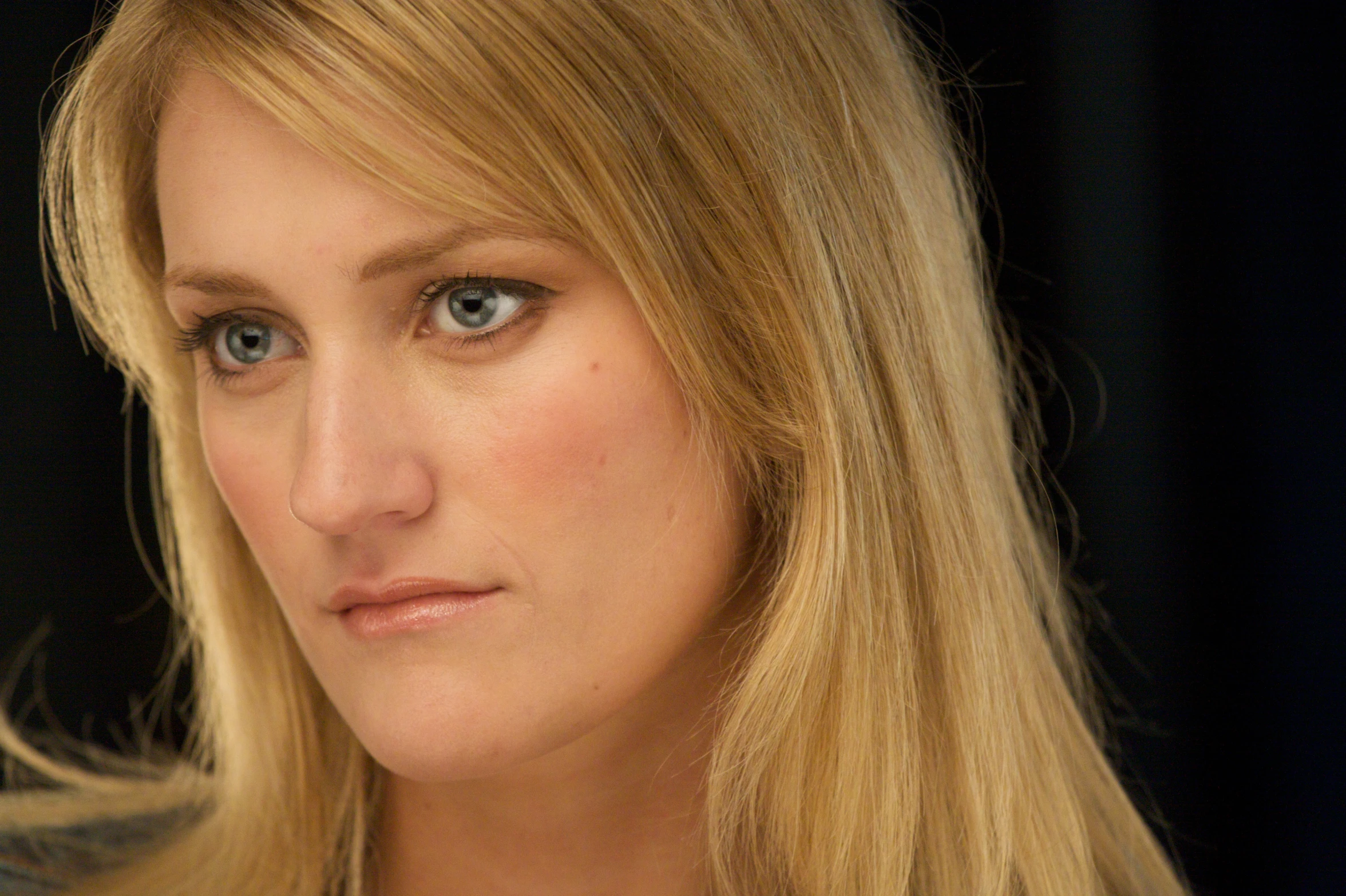 blond haired woman looking forward in studio with black background