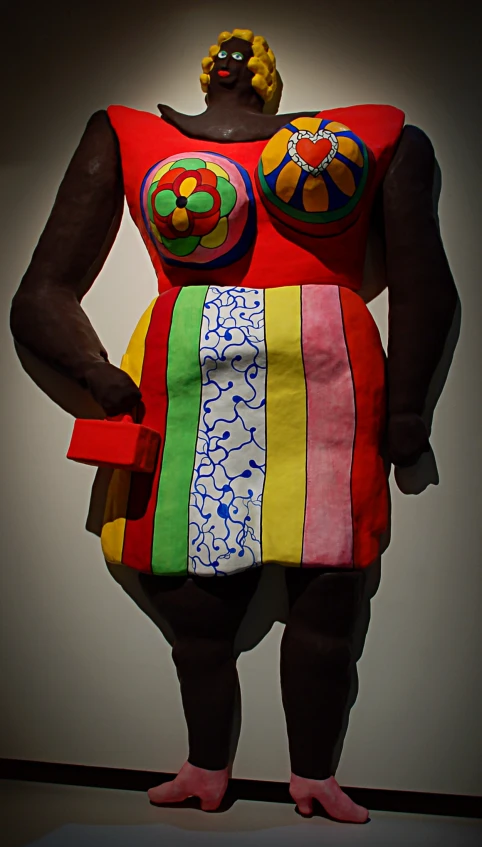 a large, colorful statue standing next to white walls