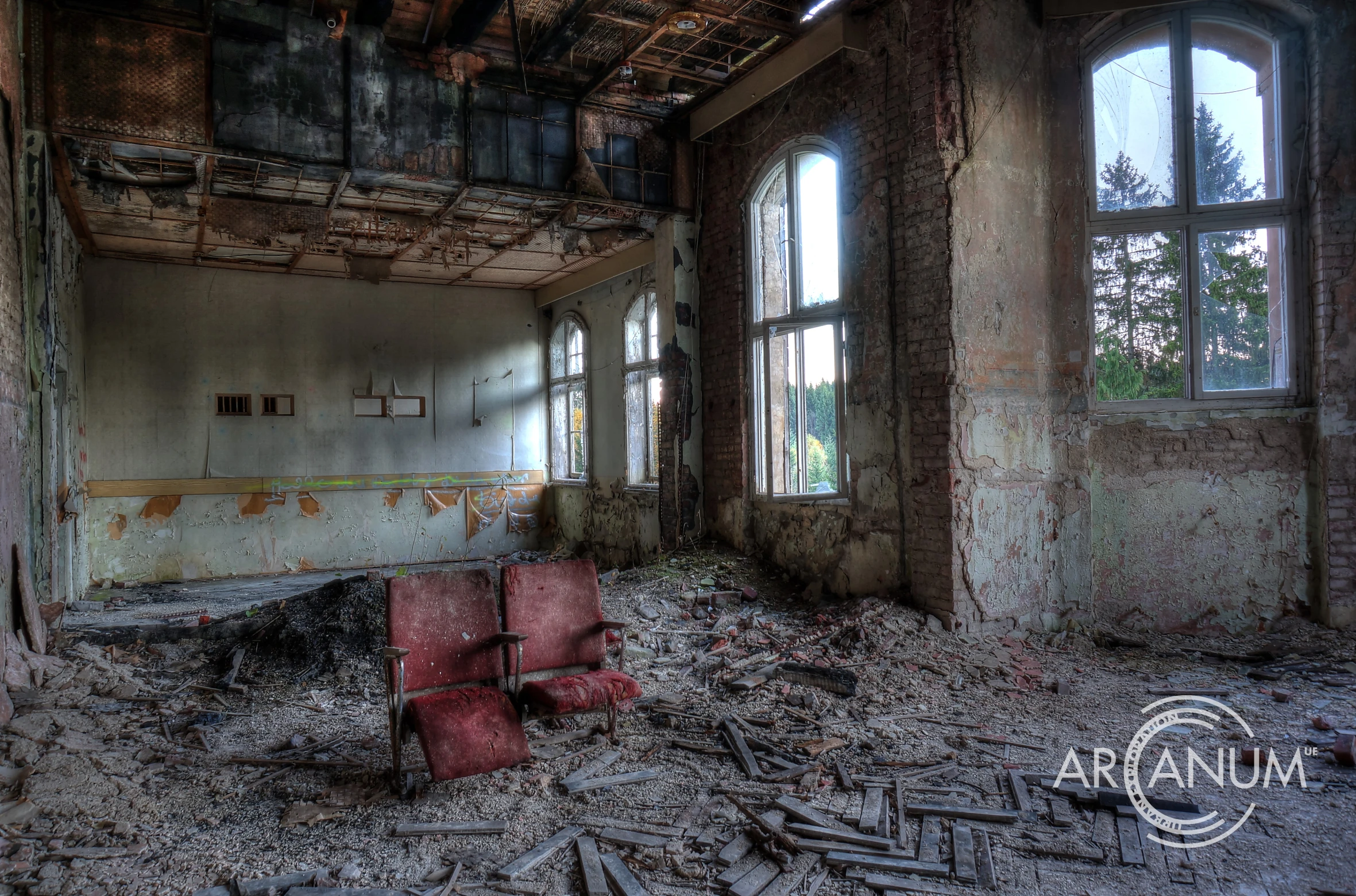 a large room with two red chairs and an old wallpaper