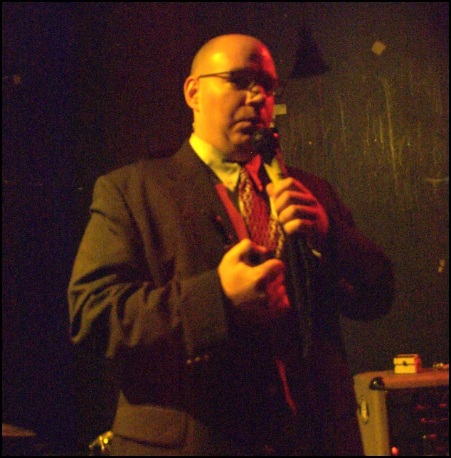 a man standing in front of a microphone with dark lighting