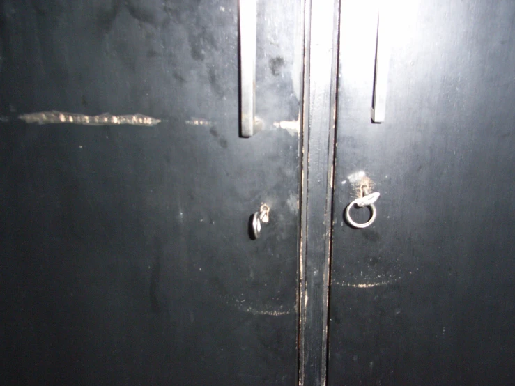 a black door and metal handles next to a white wall