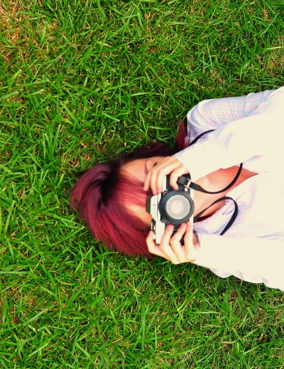 a girl is taking a picture with her camera on the grass