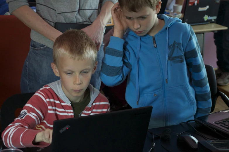 two boys sitting in front of a laptop computer