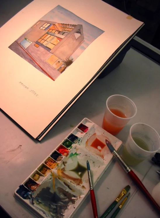 a table that has a picture, a water cup and two brushes on it