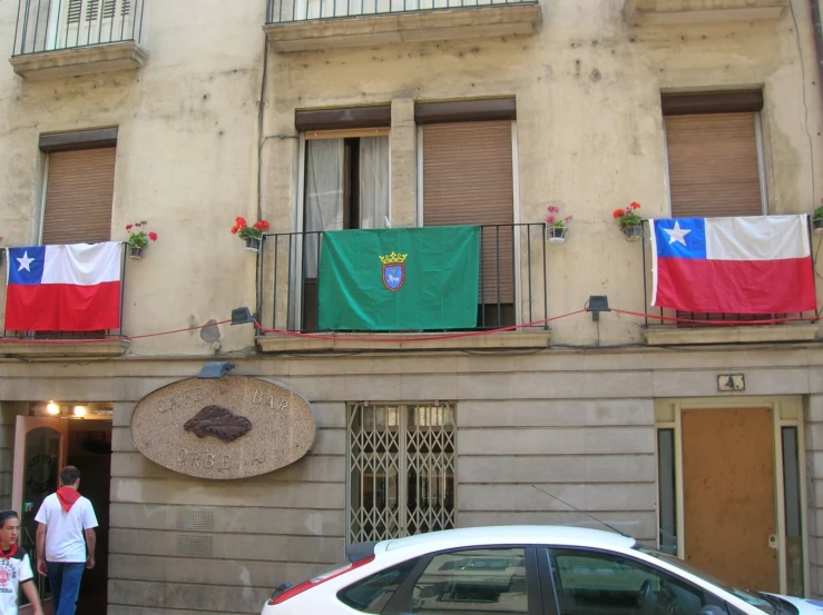 the flags are hung on the balconies above the buildings