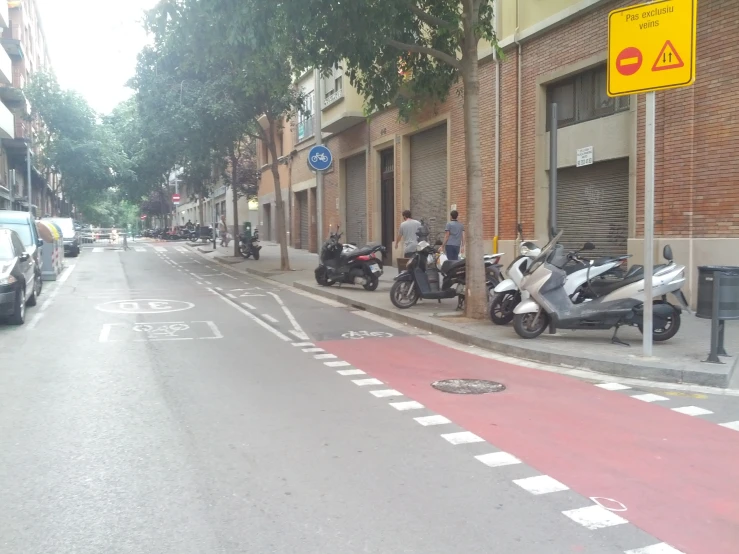 scooters parked in the street with pedestrians standing outside
