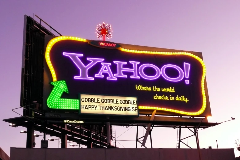 a yahoo neon sign in front of a twilight sky