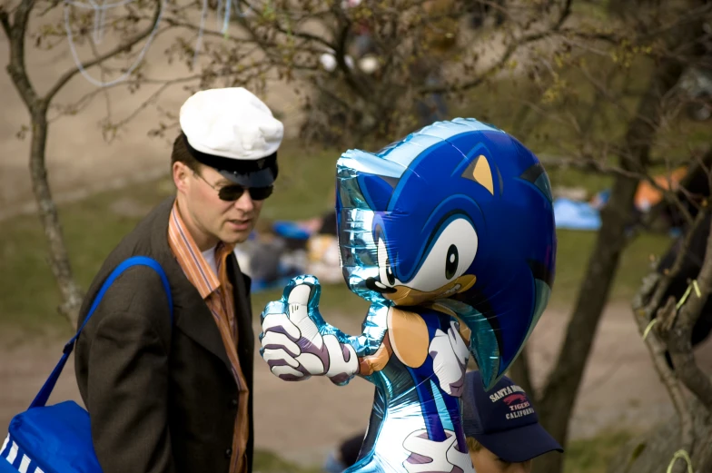 a man standing next to a giant blue sonic balloon