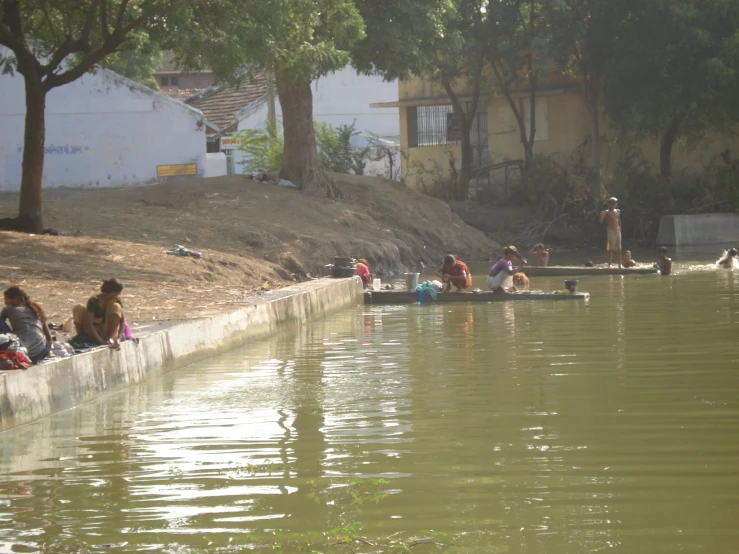 many people sitting on a wall and swimming in water