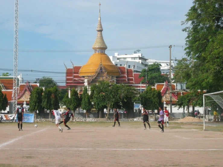 several people play soccer in a park outside a church