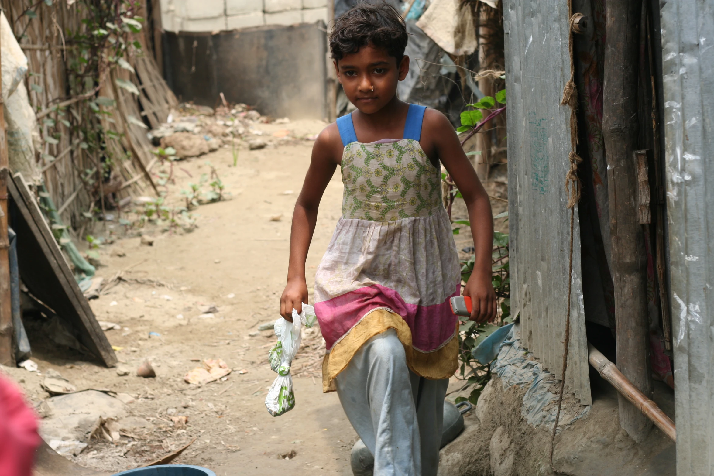 the child is walking near a building in a village