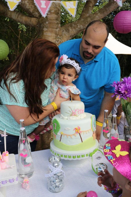 man holding up a little girl in front of a cake