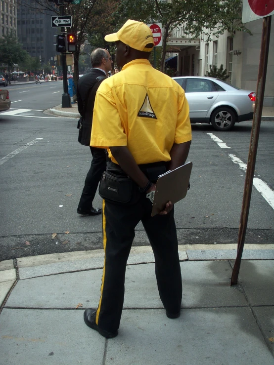 the man wearing a yellow security outfit looks to his left