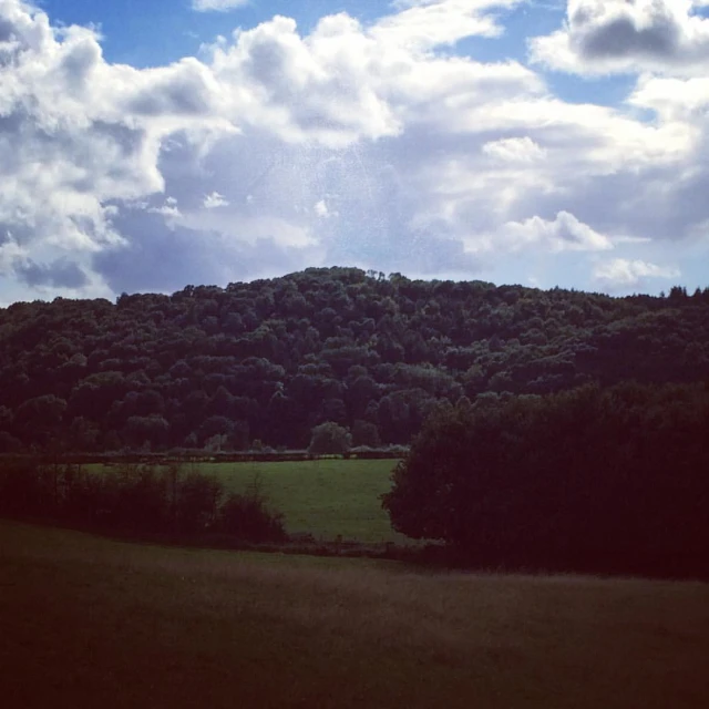 the clouds are flying over a forested mountain