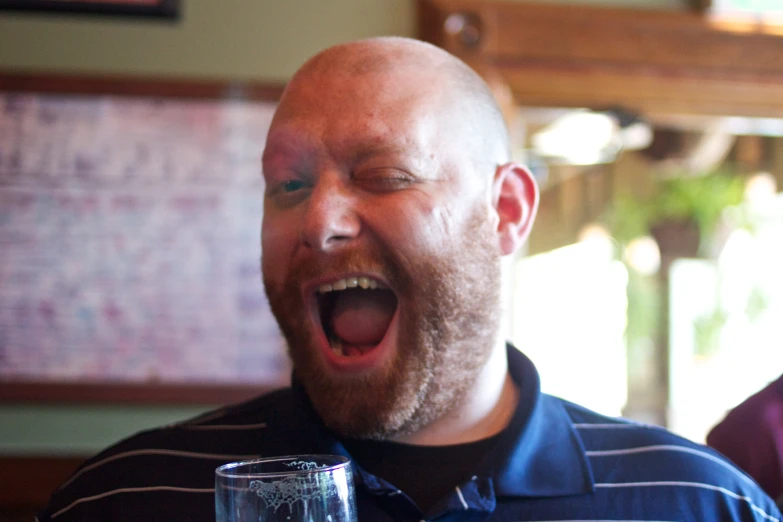 a bald man holding his glasses up to the side