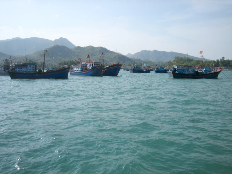 seven large fishing boats anchored together in the water