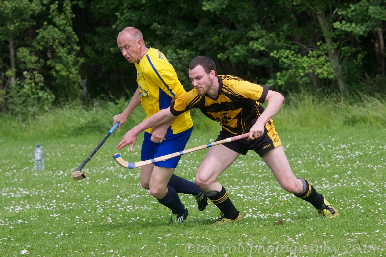 two men on opposing teams, one is holding a lacrosse racket