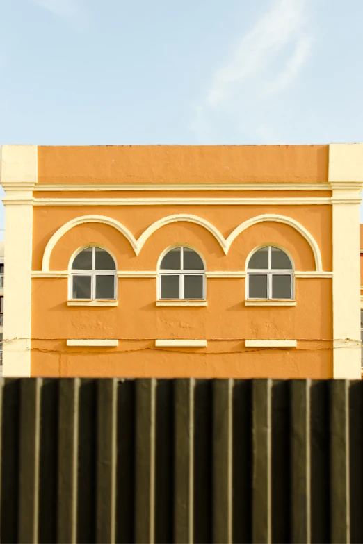 an orange building with arched windows is pographed from behind a fence