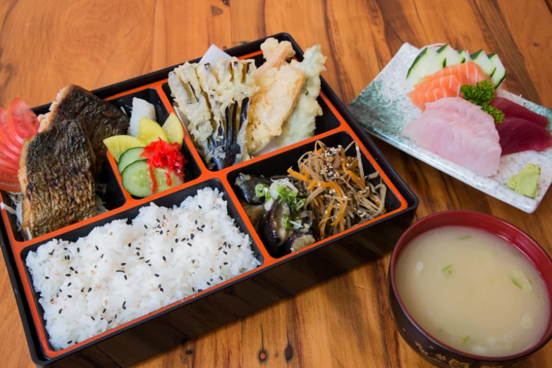 a lunchbox with a plate and container of sushi next to it