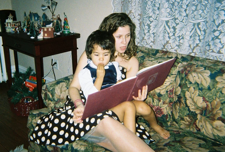 a woman sits with a child on a couch