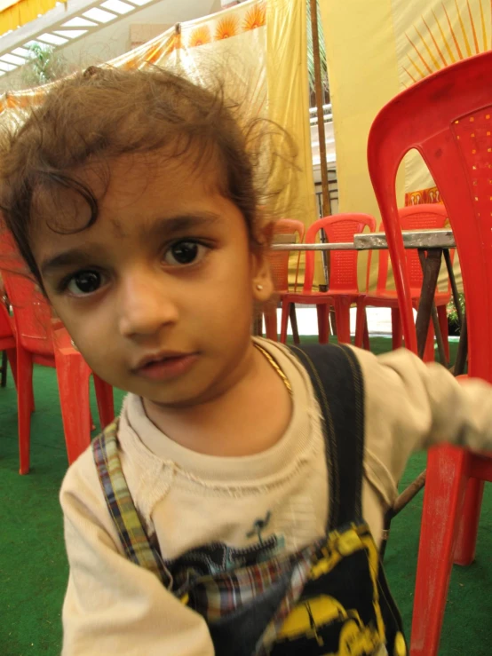 a small boy standing behind two red chairs