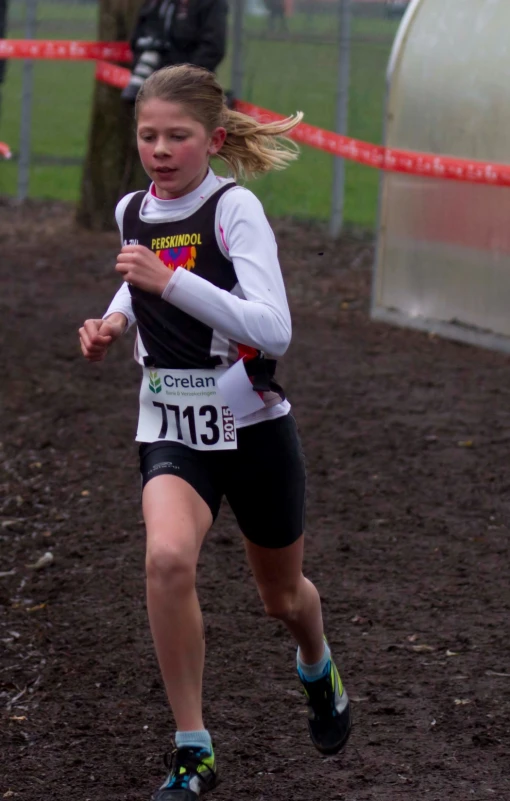 a female runner in black and white running through mud