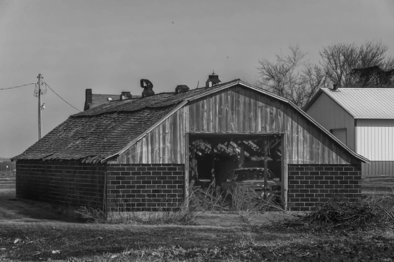 two people sitting outside a barn with a cow in the doorway