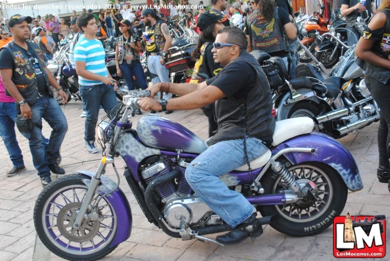 a man sitting on a motorcycle with purple paint