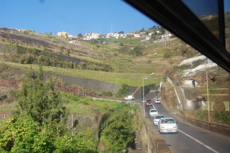 three cars drive along a hill side road