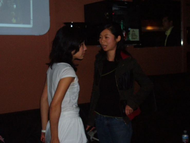 a girl in white standing next to another person in a room