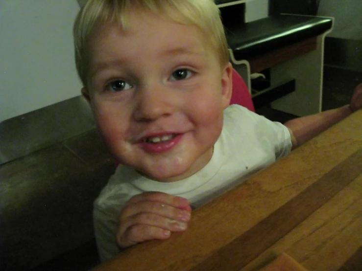 a child standing next to a wooden chair and table