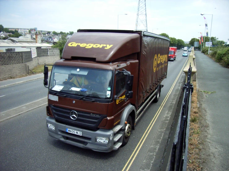 a cargo truck traveling down a street next to a fence