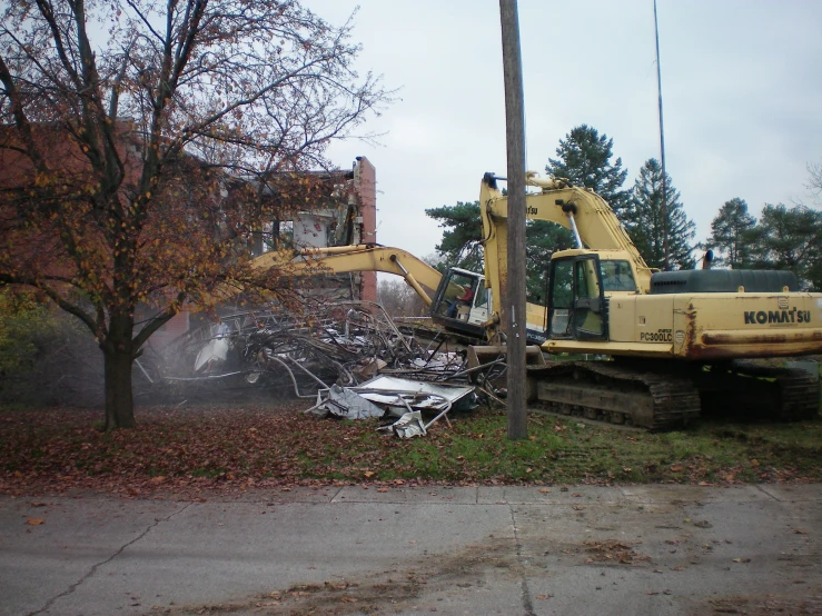 a large bulldozer digs into a pile of junk and trees