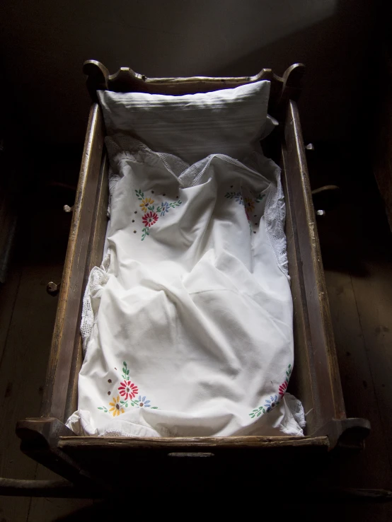 a small bed has a white and red flowered blanket