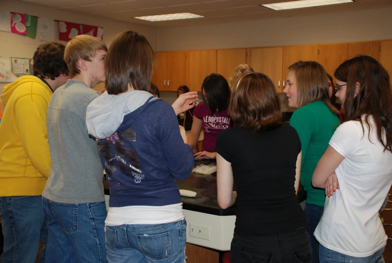 group of people gathered together looking at soing in the kitchen