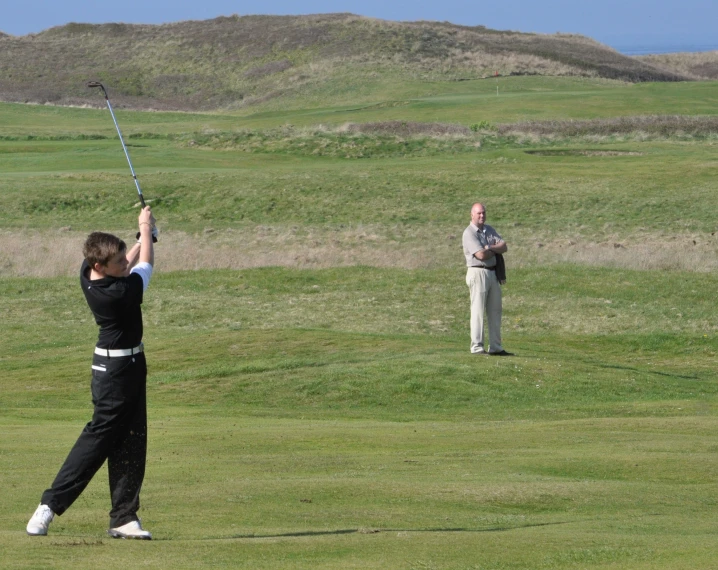 a man standing on top of a lush green golf field holding a golf club