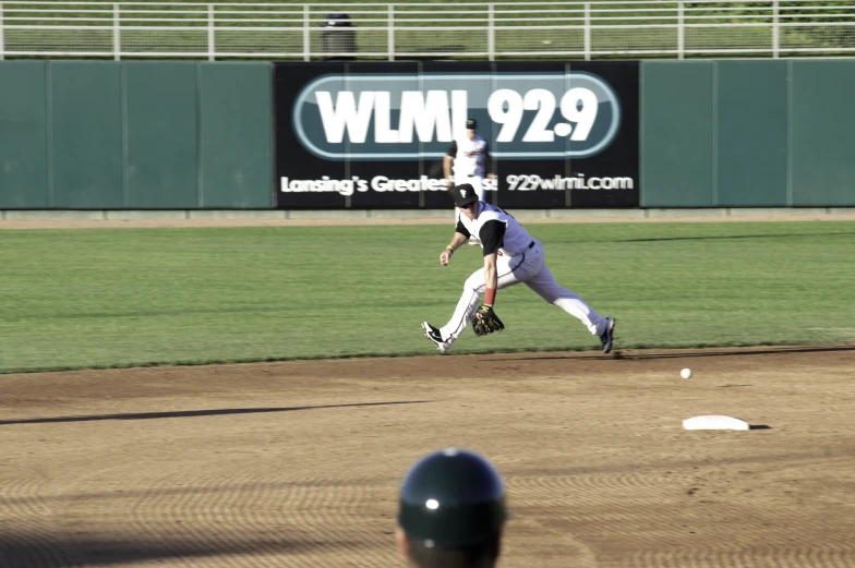 baseball player in mid air with ball going towards his foot