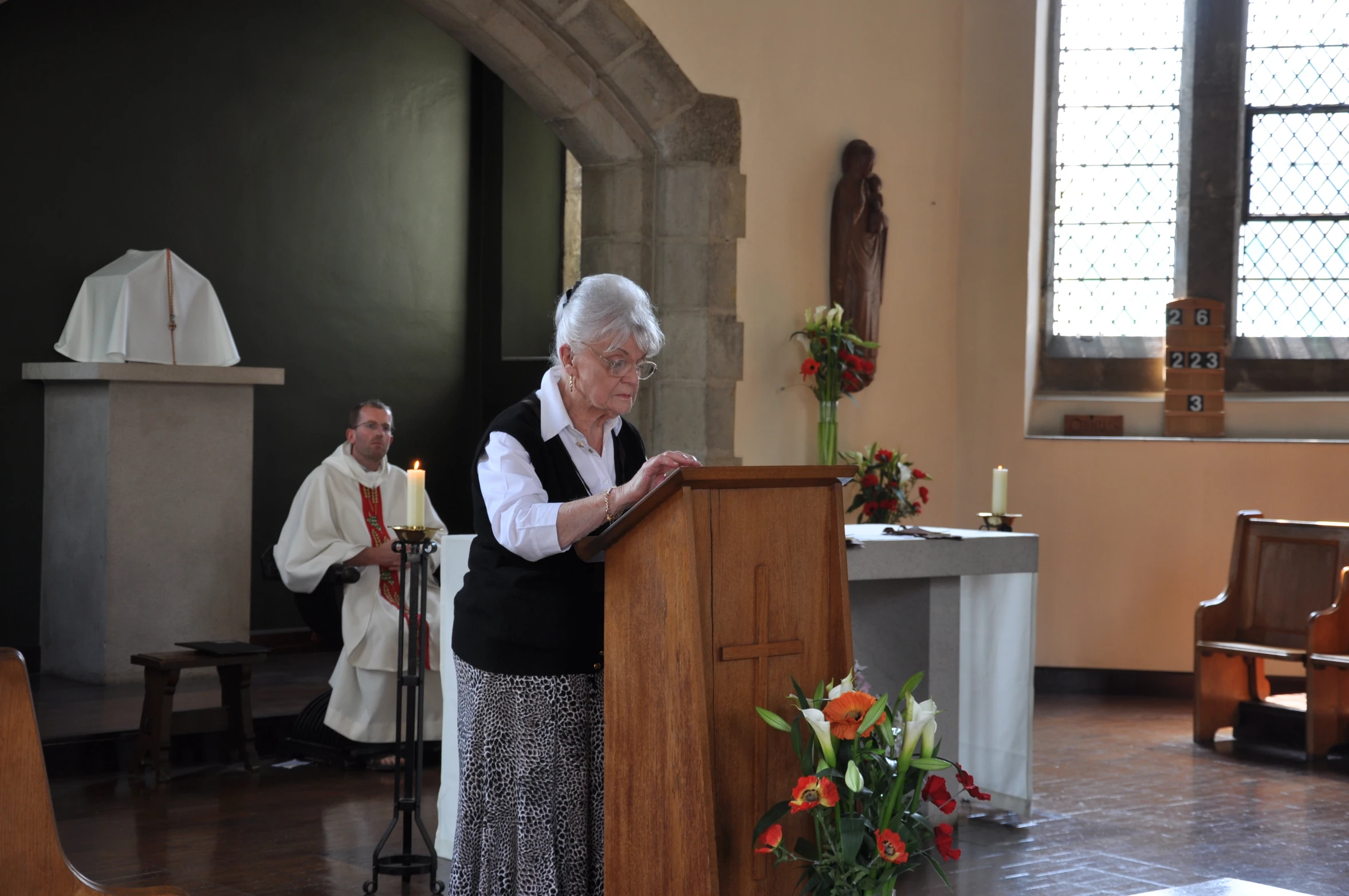 an old lady standing at a podium holding up a bible