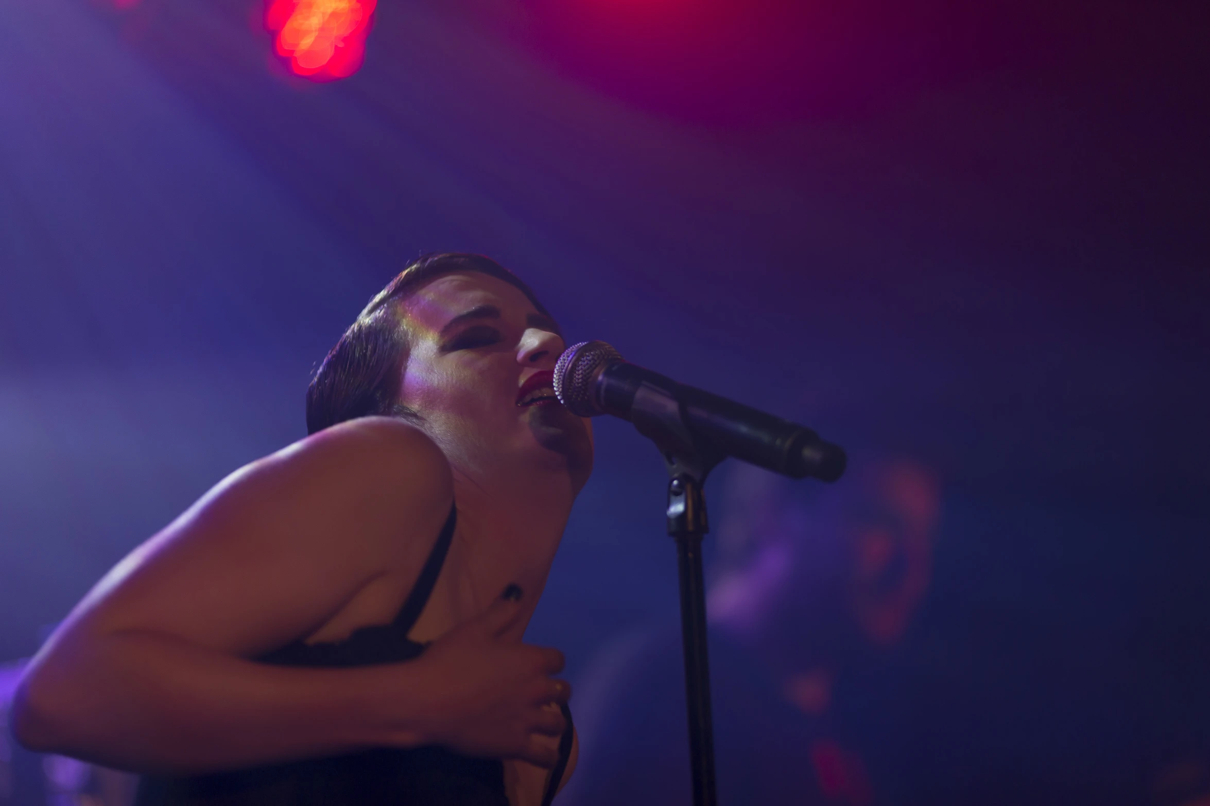 the woman is singing into the microphone in the dark