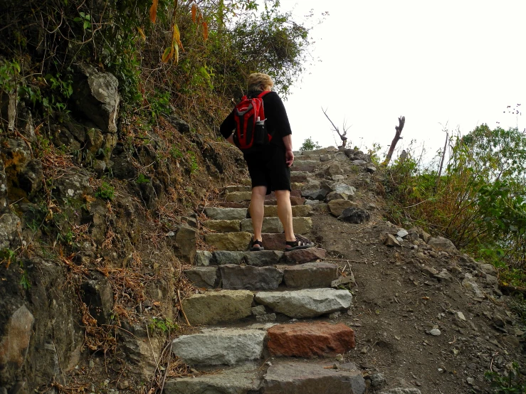 person with backpack climbing up a stone stairs