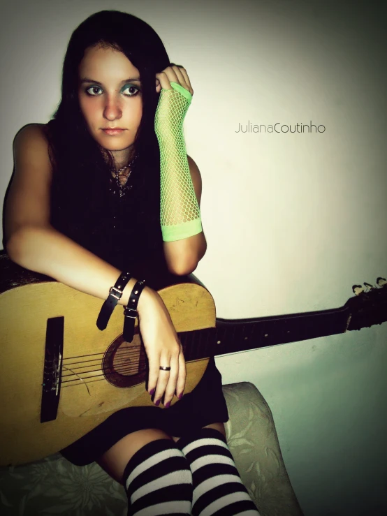 a woman sitting and holding a guitar