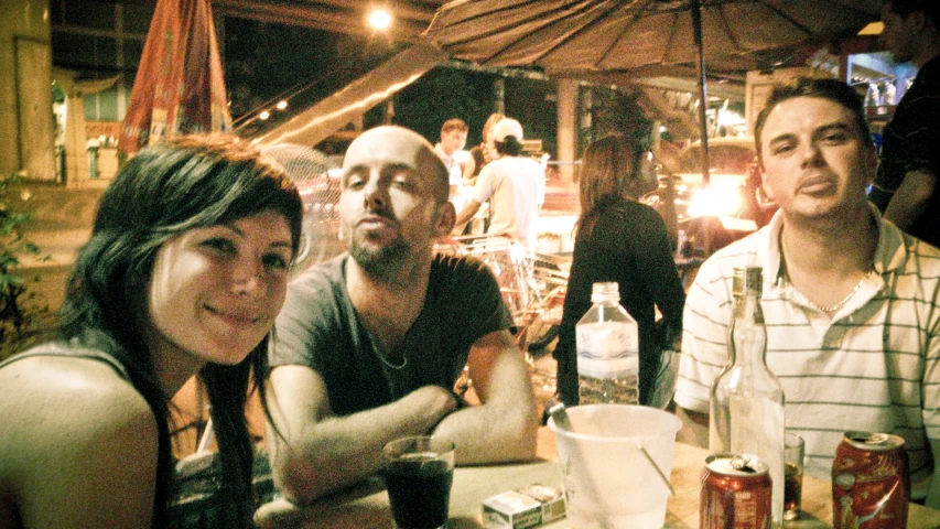 three people are smiling for the camera while sitting at a bar