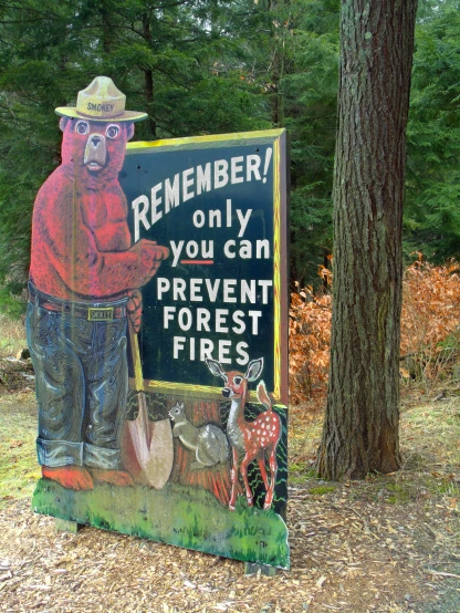 this is a sign with an animal, forest fire extinguisher, and deer