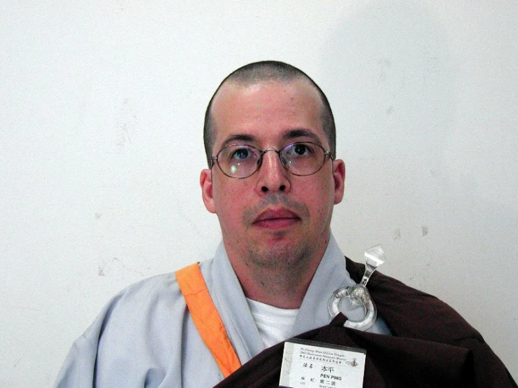 a man with glasses and a shaved head wearing glasses and a towel