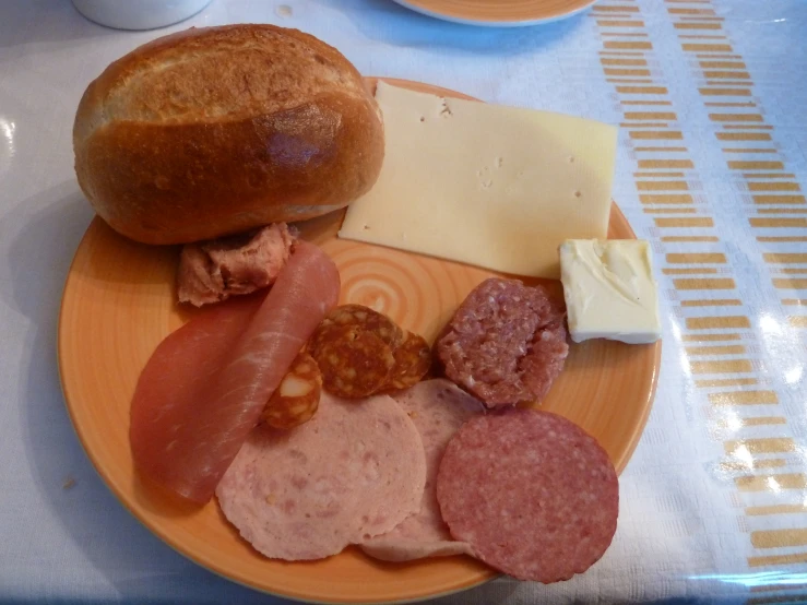 a plate of meat, cheese and bread with a piece of bread